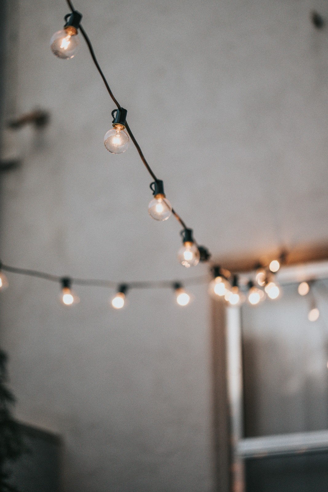 Strings of festoon bulbs glowing across a pale wall